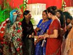 Meeting guests while the garlanded bride watches
